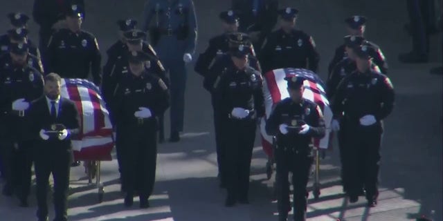 Bristol, Connecticut police officers Dustin DeMonte and Alex Hamzy walk into the 40,000-seat University of Connecticut football stadium on Friday. DeMonte and Hamzi were killed in an ambush last week.