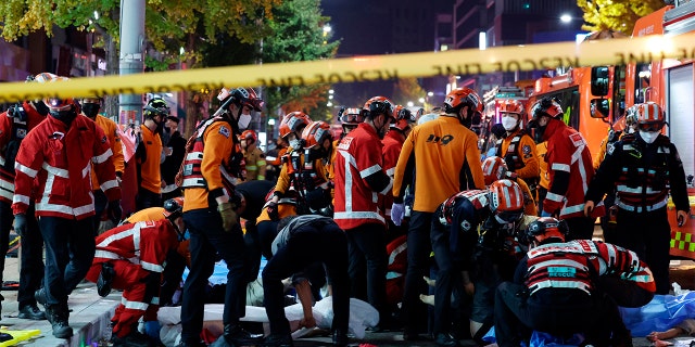 Rescue workers and firefighters work on the scene of a crushing accident in Seoul, South Korea, Saturday, Oct. 29, 2022. South Korean officials say dozens of people were in cardiac arrest after being crushed by a large crowd pushing forward on a narrow street during Halloween festivities in the capital Seoul. (Lee Ji-eun/Yonhap via AP)
