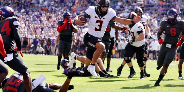 Spencer Sanders (3) of the Oklahoma State Cowboys leaps across the goal line to score a touchdown against the TCU Horned Frogs during the first half at Amon G. Carter Stadium Oct. 15, 2022, in Fort Worth, Texas.