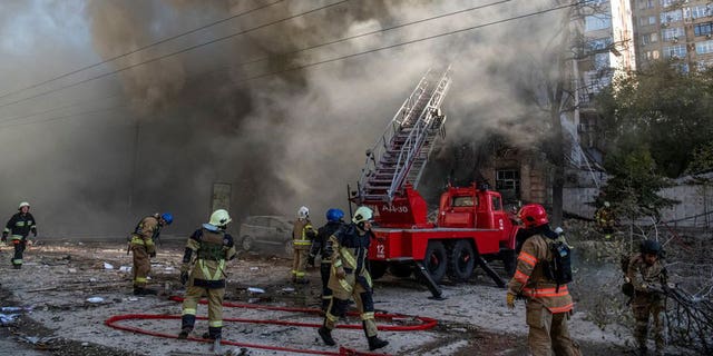 Firefighters help a woman evacuate from a residential building destroyed by a Russian drone strike, which local authorities say was an Iranian-made unmanned aerial vehicle, in Kyiv, Ukraine.