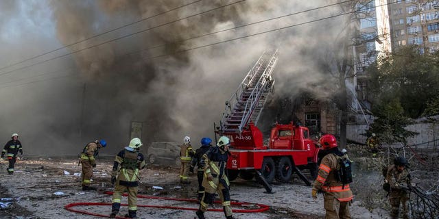 Los bomberos ayudan a una mujer local a evacuar un edificio de apartamentos destruido por un dron ruso, que las autoridades locales creen que es un vehículo aéreo no tripulado (UAV) Shahed-136 de fabricación iraní, durante el ataque ruso a Ucrania, en Kyiv, Ucrania 10 de Octubre.  17 de septiembre de 2022 (REUTERS/Vladislav Musienko)