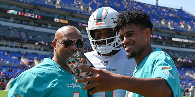 Baltimore, Maryland, USA;  Maryland Terrapins quarterback Taulia Tagovailoa takes a selfie with Miami Dolphins quarterback Tua Tagovailoa (1) and their father Galu on the sidelines before the game against the Baltimore Ravens at M&T Bank Stadium. Mandatory Credit: Tommy Gilligan-USA TODAY Sports