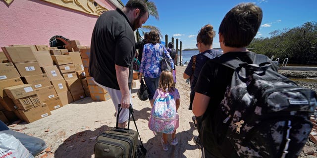 FILE - Residents who rode out the storm arrive at a dock to evacuate by boat in the aftermath of Hurricane Ian on Florida's Pine Island, in Lee County, Sunday, Oct. 2, 2022. The only bridge to the island is heavily damaged so it can only be reached by boat or air. The devastation from Hurricane Ian has left schools shuttered indefinitely in parts of Florida, leaving storm-weary families anxious for word on when and how children can get back to classrooms. (AP Photo/Gerald Herbert, File)