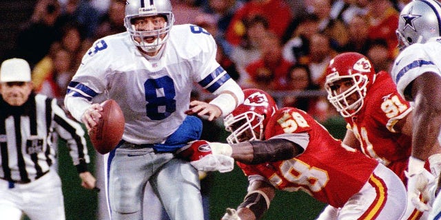 Il quarterback dei Dallas Cowboys Troy Aikman viene licenziato dal linebacker dei Kansas City Chiefs Derrick Thomas (R) a Kansas City.