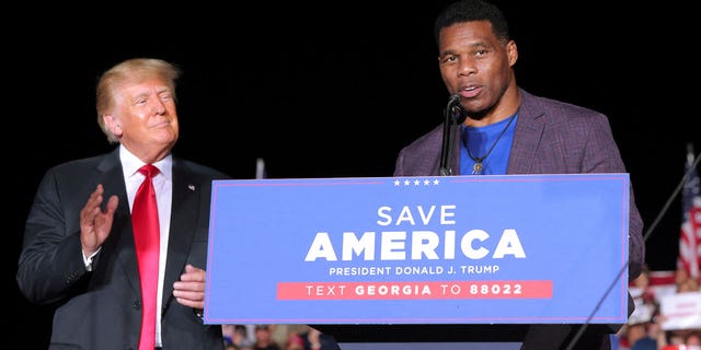 Former college football star and current senatorial candidate Herschel Walker speaks at a rally, as former President Trump applauds, in Perry, Georgia, Sept. 25, 2021.
