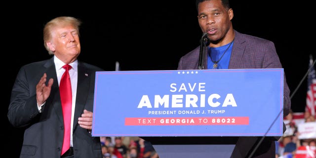 Former college football star and current senatorial candidate Herschel Walker speaks at a rally, as former President Trump applauds in Perry, Georgia, September 25, 2021.