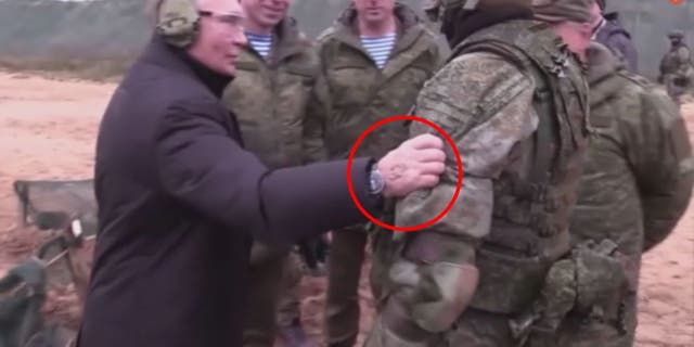 Russian President Vladimir Putin with troops. Rumors are swirling about the IV marks on Putin's hand. (APTN Screenshot)