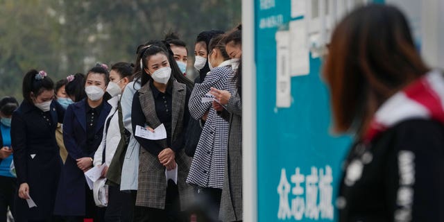 Women wearing face masks wait in line to get their routine COVID-19 throat swab tests at a coronavirus testing site in Beijing, Wednesday, Oct. 26, 2022. The Chinese city of Shanghai started administering an inhalable COVID-19 vaccine on Wednesday in what appears to be a world first. (AP Photo/Andy Wong)