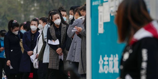 A woman wearing a face mask queues up to take a routine COVID-19 throat swab test at a coronavirus testing center in Beijing, Wednesday, Oct. 26, 2022. It seems to be the first in the world.  (AP Photo/Andy Wong)