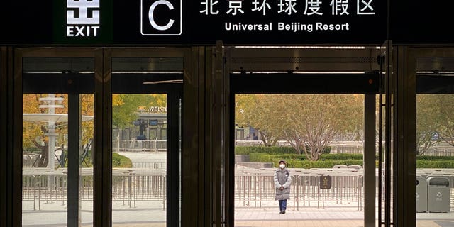 A worker wearing a face mask stands outside a subway station exit to deter visitors from visiting Universal Studios Beijing Resort, which has been closed due to Beijing's epidemic control, Wednesday, October 26, 2022. . The Chinese city of Shanghai began administering what is believed to be the world's first inhalable COVID-19 vaccine on Wednesday.  (AP Photo/Mark Siefelbein)