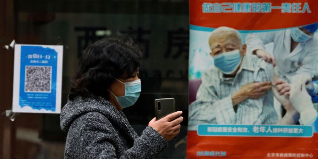 A woman wearing a mask walks by a poster promoting COVID-19 vaccination at a community health center in Beijing, Wednesday, October 26, 2022. The Chinese city of Shanghai began administering her inhalable COVID-19 vaccine on Wednesday. Be the first in the world.  (AP Photo/Andy Wong)