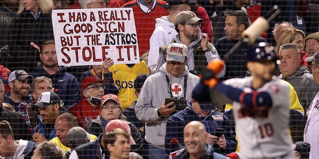 A sign referring to the Astros' cheating scandal is held by a fan during the Red Sox game against Houston during the American League Championship Series at Fenway Park on Oct. 18, 2021, in Boston.