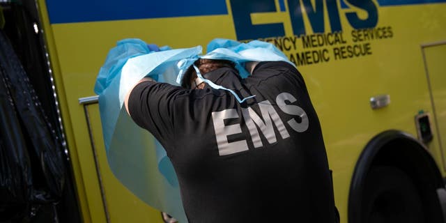 یک پزشک با EMS کانتی آستین تراویس پس از سوار کردن مردی با علائم احتمالی کووید-19 در آمبولانس، لباس‌های محافظ را برمی‌دارد.