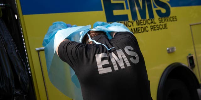 An Austin-Travis County EMS doctor removes protective clothing after loading a man with possible symptoms of COVID-19 into an ambulance.