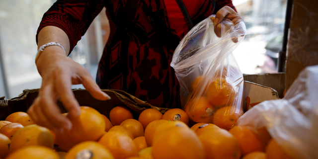 A customer places oranges into a plastic bag at a grocery store in Toronto on Wednesday, June 12, 2019. Justin Trudeau's government announced plans Monday to ban single-use plastics such as straws and plates in Canada.