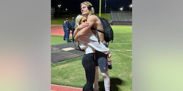 Murder victim Elijah DeWitt, right, hugs his girlfriend of four years, Bailey Reidling, on the football field.