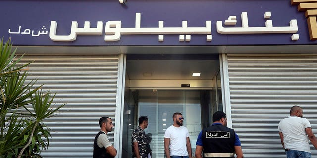 Lebanese security officers stand at the entrance of a Byblos Bank branch that was broken into by depositor Ali Hodroj. Hodroj held a handgun, fired a warning shot and demanded about $40,000 of his trapped savings, in Tyre, south Lebanon, on Oct. 4, 2022. 