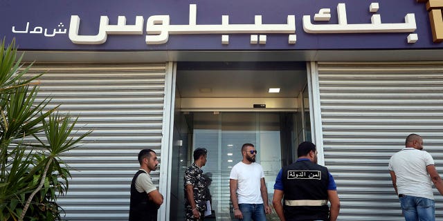 Lebanese security officers stand at the entrance of a Byblos Bank branch that was broken into by depositor Ali Hodroj. Hodroj held a handgun, fired a warning shot and demanded about $40,000 of his trapped savings, in Tyre, south Lebanon, on Oct. 4, 2022.