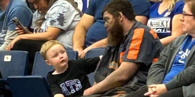 Coal miner Michael McGuire sits with his son, Easton, to watch the Wildcats' Blue-White scrimmage in Pikeville, Kentucky.