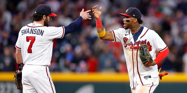 Dansby Swanson #7 and Ronald Acuna Jr. #13 of the Atlanta Braves celebrate the 4-2 victory over the New York Mets at Truist Park on October 1, 2022 in Atlanta, Georgia.