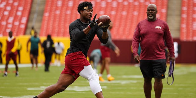 Brian Robinson #8 of the Washington Commanders warms up with running backs coach Randy Jordan before the game against the Philadelphia Eagles at FedExField on Sept. 25, 2022 in Landover, Maryland. Robinson was shot twice in the leg during an attempted robbery on Aug. 28, 2022.