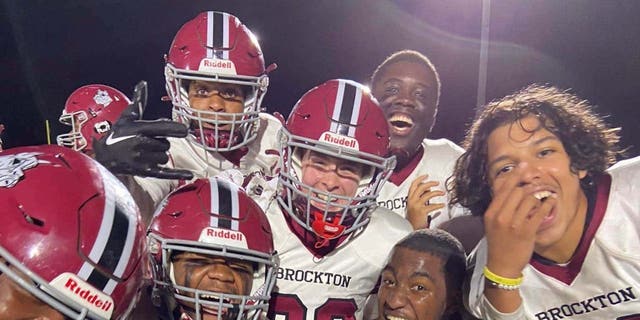 Brockton High School football players surround McKenzie Quinn center) after scoring her first touchdown on Oct. 7, 2022.