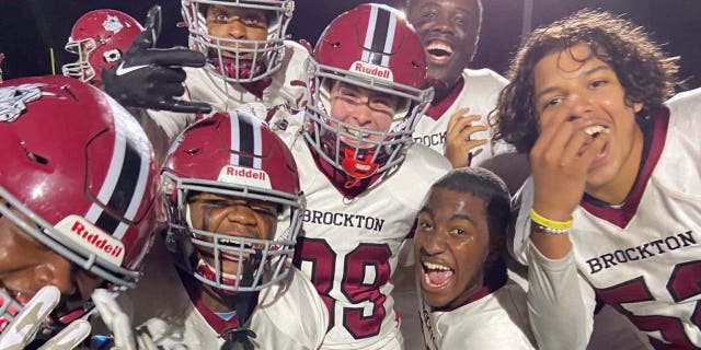 Brockton High School football players surround McKenzie Quinn center) after scoring her first touchdown on Oct. 7, 2022.