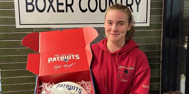 McKenzie Quinn, the first female Brockton High School football player to score a touchdown in a varsity game, holds an autographed football from the New England Patriots and owner Robert Kraft.