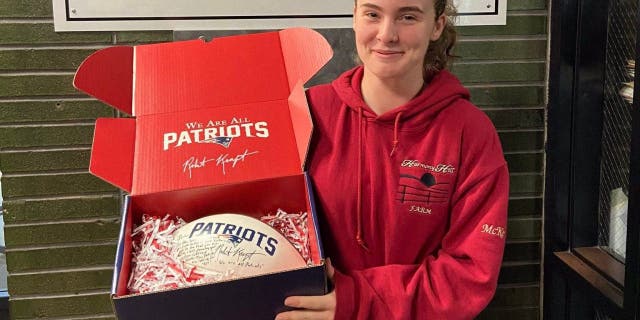 McKenzie Quinn, the first female Brockton High School football player to score a touchdown in a varsity game, holds an autographed football from the New England Patriots and owner Robert Kraft.