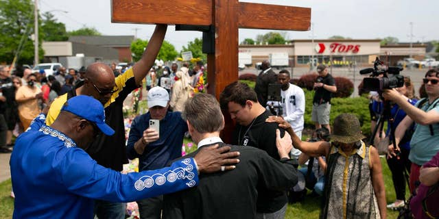 A group of people are seen praying at a memorial site for the victims of a racist mass shooting at a supermarket on May 21, 2022, in Buffalo, New York.