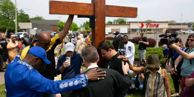 A group of people are seen praying at a memorial site for the victims of a racist mass shooting at a supermarket on May 21, 2022, in Buffalo, New York.