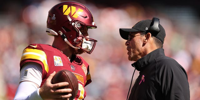 Carson Wentz #11 of the Washington Commanders talks with head coach Ron Rivera during the first half against the Tennessee Titans at FedExField on Oct. 9, 2022 in Landover, Maryland.