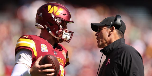 Carson Wentz talks with Washington Commanders coach Ron Rivera during the Tennessee Titans game at FedExField on Oct. 9, 2022, in Landover, Maryland.