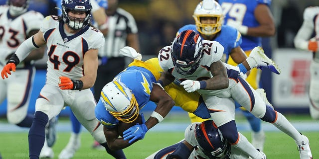 Joshua Palmer #5 of the Los Angeles Chargers is brought down by K'Waun Williams #21 and Kareem Jackson #22 of the Denver Broncos during the second half at SoFi Stadium on October 17, 2022 in Inglewood, California.