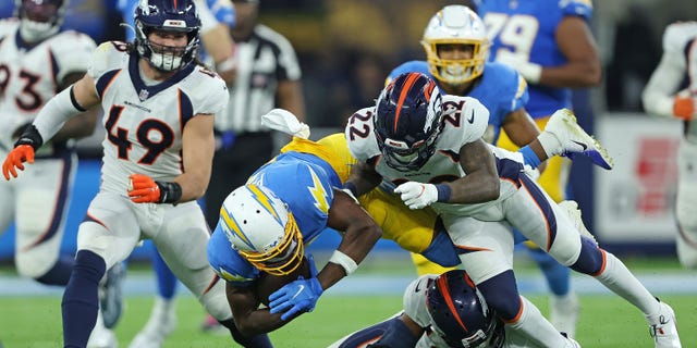 Joshua Palmer, #5 of the Los Angeles Chargers, is brought down by K'Waun Williams, #21, and Kareem Jackson, #22 of the Denver Broncos, during the second half at SoFi Stadium on Oct. 17, 2022 in Inglewood, California.