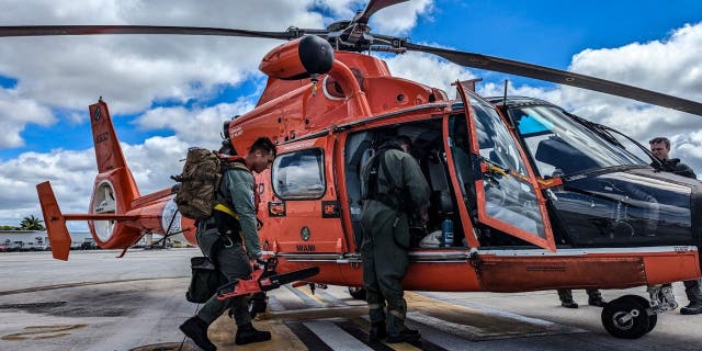 U.S. Coast Guard members board a helicopter in the aftermath of Hurricane Ian.