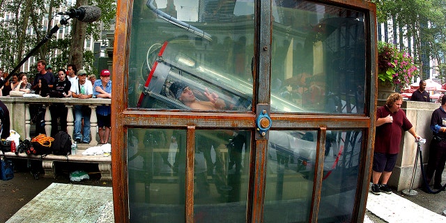 Illusionist Criss Angel flashes a peace sign from inside an airtight container submerged in a 2,000-gallon tank of water from which he will have 33 hours to escape as he performs "Oasis," his most challenging escape yet, in Bryant Park.