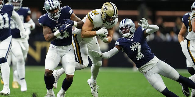 Micah Parsons (11) and Trevon Diggs (7) of the Dallas Cowboys tackle Nick Vannett of the New Orleans Saints on Dec. 2, 2021, in New Orleans.