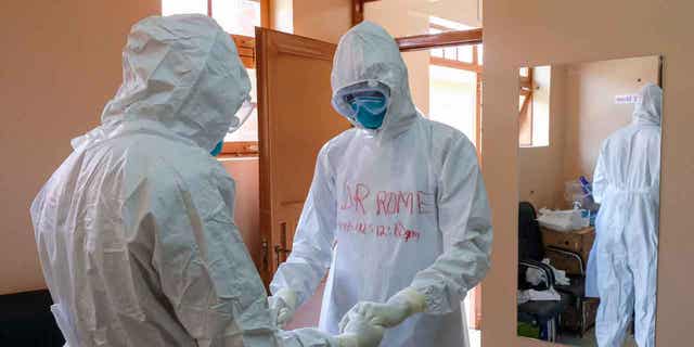 Doctors wearing protective equipment pray together before they visit a patient who was in contact with an Ebola victim, in the isolation section of Entebbe Regional Referral Hospital in Entebbe, Uganda, on Oct. 20, 2022.