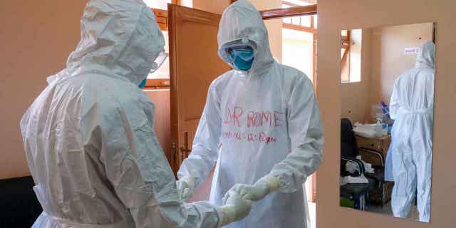 Doctors wearing protective gear pray together before visiting a patient who came into contact with an Ebola victim in the isolation ward of the Entebbe Regional Referral Hospital in Entebbe, Uganda, in October. 20, 2022.