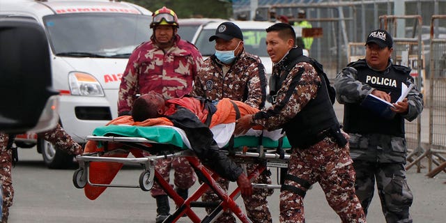 Prison guards evacuate an injured prisoner following clashes between inmates at the Regional Sierra Centro Norte Cotopaxi prison in Latacunga, Ecuador, on Oct. 4, 2022. 