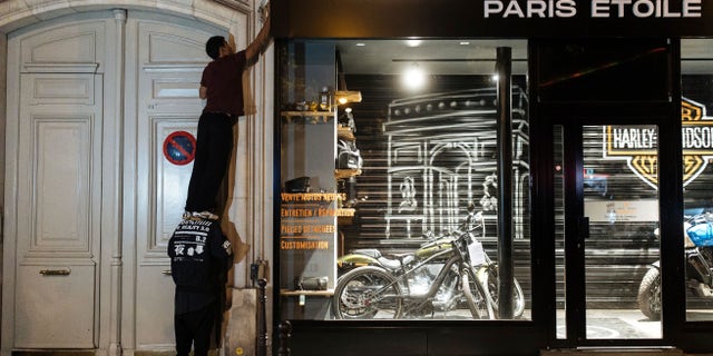 The "On the Spot" collective in France turns off lights at a Paris storefront during a night of action on July 29, 2022, in an effort to save energy ahead of a possible energy crisis in Europe.