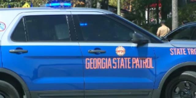 A Georgia State Patrol car sits at a cordoned off crime scene.