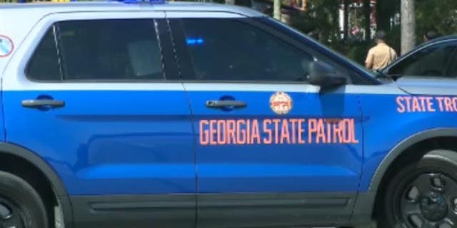 A Georgia State Patrol car sits at a roped off crime cene.