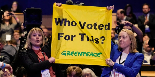 Protesters hold a banner as Britain's Prime Minister Liz Truss makes a speech at the Conservative Party conference at the ICC in Birmingham, England, on Wednesday.