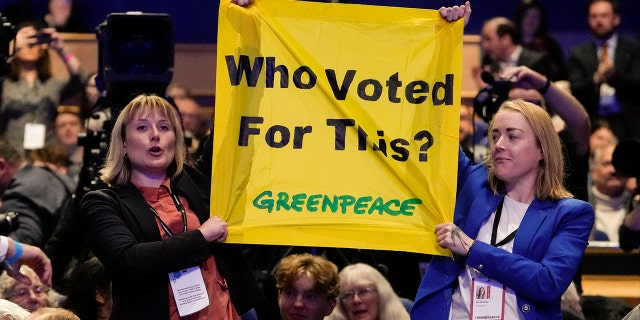 Protesters hold a banner as Britain's Prime Minister Liz Truss makes a speech at the Conservative Party conference at the ICC in Birmingham, England, on Wednesday.