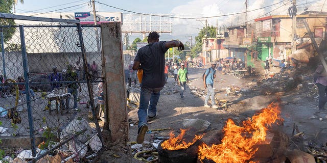A man runs away from fire burning in the streets during a protest in the Petion-Ville area of Port-au-Prince, Haiti, on Oct. 3, 2022. The protests occurred after Prime Minister Ariel Henry announced that the government could no longer afford fuel subsidies, and that prices would have to be increased. 