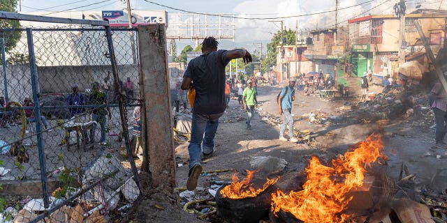 A man runs away from fire burning in the streets during a protest in the Petion-Ville area of Port-au-Prince, Haiti, on Oct. 3, 2022. The protests occurred after Prime Minister Ariel Henry announced that the government could no longer afford fuel subsidies, and that prices would have to be increased.