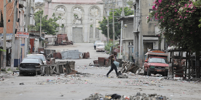 A man walks between roadblocks set up by gangs after they engaged in intense gun battles, closing major avenues and the municipal market in the center of the capital, in Port-au-Prince, Haiti, on July 27, 2022. 