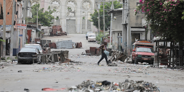 A man walks among roadblocks set up by gangs after they conducted intense firefights, closing main streets and a municipal market in the center of the capital, in Port-au-Prince, Haiti, on July 27, 2022. 